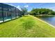 Landscaped backyard featuring a screened-in pool and access to a serene lake at 3341 Pawleys N Loop, St Cloud, FL 34769