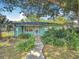 Inviting single-story home with a light blue exterior, complemented by lush greenery and a quaint walkway at 401 Maryland Ave, St Cloud, FL 34769