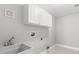 This is a simple laundry room with a utility sink, white cabinets, and tile flooring at 430 Bywater Dr, Orlando, FL 32839