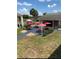 Community outdoor seating area with tables, chairs, red umbrellas, and lush green landscaping at 5245 W Irlo Bronson Memorial Hwy # 194, Kissimmee, FL 34746