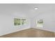 Bedroom with vaulted ceiling, wood-look floors, and large windows with green backyard views at 5851 Se Drew Rd, Belleview, FL 34420