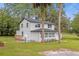 A charming two-story home with a welcoming front porch framed by lush greenery and mature palm trees at 5851 Se Drew Rd, Belleview, FL 34420
