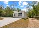 Newly renovated one-story home featuring a white exterior, minimalist design, concrete driveway, and natural setting at 610 E Euclid Ave, Deland, FL 32724