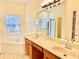 Bathroom featuring a double vanity, large mirror, and a relaxing soaking tub next to a window at 671 Carey Way, Orlando, FL 32825