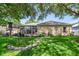 Landscaped backyard featuring a sunroom, pergola, and well-manicured lawn, creating a serene outdoor living space at 714 Regina Cir, Oakland, FL 34787