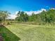 Large grassy backyard showcasing a serene view of the woods and manicured shrubbery at 1029 Umbria Dr, Poinciana, FL 34759