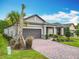 Beautiful single-story home shows a manicured lawn, brick paved drive and a two car garage at 1029 Umbria Dr, Poinciana, FL 34759