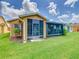 Exterior view of enclosed back porch, surrounded by green grass and landscaping at 112 Grand Canal Dr, Poinciana, FL 34759