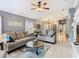 Inviting living room with tile flooring, ceiling fan, and two gray sofas with blue accent pillows at 112 Grand Canal Dr, Poinciana, FL 34759