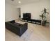 Contemporary living room featuring light tile flooring, black leather furniture, and a decorative potted plant at 19235 Allium Pl, Orlando, FL 32827