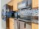 Modern kitchen with granite countertops, stainless steel appliances, and mosaic tile backsplash at 207 Bailey Cir, Davenport, FL 33897