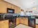 Functional kitchen with black appliances, light wood cabinets, granite countertops, and a decorative backsplash at 207 Bailey Cir, Davenport, FL 33897