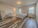 Cozy bedroom with wood-look floors, a white bed, neutral walls, and an ensuite bathroom at 2310 Raven Ridge Rd, Minneola, FL 34715