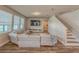 Inviting living room with a plush sectional sofa, large windows, and a staircase at 2310 Raven Ridge Rd, Minneola, FL 34715