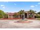 Stately brick home featuring a circular driveway, large fountain, mature landscaping, and grand entrance, with a red tile roof at 2841 S Lloyd Ln, Kissimmee, FL 34744