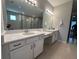 Bright bathroom featuring dual vanities, white cabinets, quartz countertop, and a large mirror reflecting a tiled shower at 2920 Agostino Ter, Kissimmee, FL 34746