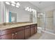 Modern bathroom features dual sinks, granite countertops, a glass-enclosed shower, and tile flooring at 2985 Banana Palm Dr, Kissimmee, FL 34747