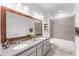 Modern bathroom with a double sink vanity, granite countertops, a large mirror, and a shower-tub combo at 33263 Rembrandt Ln, Sorrento, FL 32776