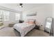 Cozy bedroom with neutral carpet, a ceiling fan, a bed with patterned bedding, and natural light from a window at 33263 Rembrandt Ln, Sorrento, FL 32776