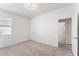 Bright bedroom with neutral carpet, a window with blinds, overhead lighting, and a doorway leading to the hallway at 33263 Rembrandt Ln, Sorrento, FL 32776