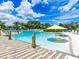 Large community pool with clear blue water, lounge chairs, and palm trees under a partly cloudy sky at 349 Captiva Dr, Davenport, FL 33896