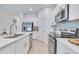 White kitchen with stainless steel appliances, sleek cabinetry, and a view into an adjacent dining area at 3617 Anibal St, Kissimmee, FL 34746