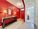 Inviting foyer with elegant tile flooring, stylish console table, and bright red accent wall with a mirror at 3690 Maidencain St, Clermont, FL 34714