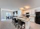 Open kitchen layout with island and barstool seating, connected to dining area with black refrigerator at 3690 Maidencain St, Clermont, FL 34714