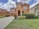 Two-story home with arched windows, a tower feature and well-manicured landscaping at 394 Orange Cosmos Blvd, Davenport, FL 33837