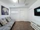 The living room is cozy with a futon sofa, a TV and access to two doors at 394 Orange Cosmos Blvd, Davenport, FL 33837