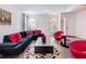 Living room showcases a black sofa with red cushions, unique chairs, and lots of natural light at 394 Orange Cosmos Blvd, Davenport, FL 33837