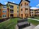 Attractive condo building with spacious balconies, beautiful landscaping, and a comfortable bench seating area at 5451 Vineland Rd # 111, Orlando, FL 32811