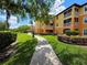Well-maintained condo building featuring lush landscaping and a paved walkway on a bright, sunny day at 5451 Vineland Rd # 111, Orlando, FL 32811