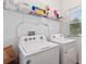 Bright laundry room with white washer and dryer and overhead storage shelves at 5816 Beefmaster Rd, St Cloud, FL 34771