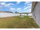 Large backyard with a white fence, grassy lawn, small tree, swing set, and a concrete patio at 604 Kangaroo Dr, Poinciana, FL 34759