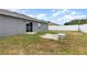 Spacious backyard featuring a gray house, white fence, sliding glass door, and a small seating area at 604 Kangaroo Dr, Poinciana, FL 34759