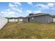 Spacious backyard featuring a gray house, white fence, sliding glass door, and a swing set at 604 Kangaroo Dr, Poinciana, FL 34759