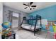 Colorful ' bedroom with a bunk bed, a globe, and playful dinosaur-themed decor on a bright blue wall at 604 Kangaroo Dr, Poinciana, FL 34759