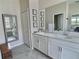Elegant bathroom with double sinks, white cabinetry, quartz countertops, and decorative mirrors at 703 Ocean Course Ave, Davenport, FL 33896
