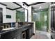 Modern bathroom featuring dual sinks, sleek black countertops, and a green tiled shower for a spa-like experience at 7503 Mourning Dove Cir # 101, Reunion, FL 34747