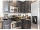 Modern kitchen with sleek stainless steel appliances, granite counters, and dark cabinets at 7503 Mourning Dove Cir # 101, Reunion, FL 34747