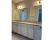 Bathroom vanity with double sinks, gray counters, and modern light fixtures at 9938 Eagle Creek Center Blvd, Orlando, FL 32832