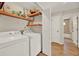 Laundry room featuring a washer, dryer, wood shelving, and neutral wall color leading into a nearby bathroom at 1050 Dees Dr, Oviedo, FL 32765