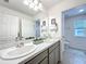 Bright bathroom featuring double sinks, gray cabinetry, and neutral decor at 1181 Lone Palm Way, St Cloud, FL 34771