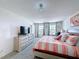 Bright bedroom with a striped bedspread, TV, light fixture, and large windows at 1181 Lone Palm Way, St Cloud, FL 34771