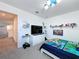 Bright bedroom with white walls, gray carpet, television, and fun decor on display at 1181 Lone Palm Way, St Cloud, FL 34771