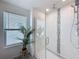 Glass enclosed shower with a rainfall showerhead, a plant, and white tile at 1181 Lone Palm Way, St Cloud, FL 34771