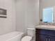 Modern bathroom with a tiled bathtub, a dark wood vanity, and a sink with granite countertop at 12313 Prairie Plantation Way, Orlando, FL 32824