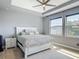 This bedroom features a tray ceiling, two large windows for natural lighting, and neutral-colored walls at 12313 Prairie Plantation Way, Orlando, FL 32824