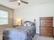 This bedroom features a ceiling fan, a window for natural lighting, and a decorative dark wood dresser at 12313 Prairie Plantation Way, Orlando, FL 32824
